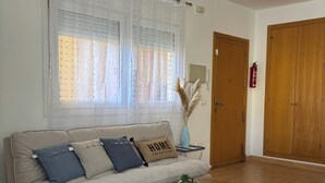 Una sala de estar con un sofá color beige, una mesa de centro de madera y un sillón blanco.