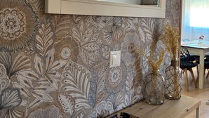 Una habitación con papel tapiz floral, una consola de madera con un atril decorativo y un espejo encima.