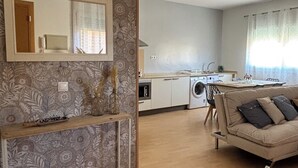Una sala de estar moderna con un sofá, una consola y una cocina al fondo.