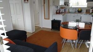 Een moderne keuken met witte kasten, een zwarte kookplaat en een eethoek met oranje stoelen.