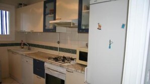 Una cocina compacta con estufa a gas, horno y refrigerador blanco.