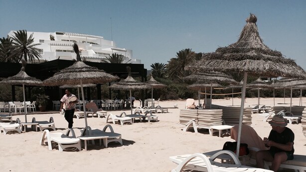 Zona de playa con tumbonas, sombrillas y algunas personas.