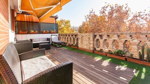 A patio with wicker furniture, a brick wall, and a wooden deck.