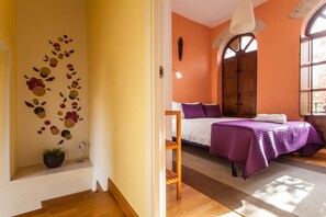A room with a bed, a wooden shelf, and a wall with a floral decoration. - Duplex penthouse in Sevilla centre. Wifi, AC, large terrace, excellent views. (Sevilla)