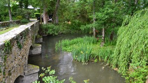 A stone bridge over a calm river surrounded by lush greenery.