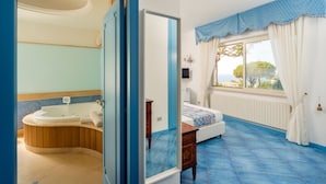A bathroom with a bathtub, a mirror, and a window with curtains.