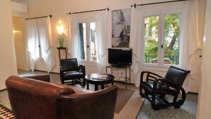 A living room with a sofa, two chairs, a small table, a TV, and a window with curtains. - Lovely and quite apartment with garden in the heart of Venice (Venice)