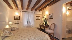 A bedroom with a large bed, a desk, a chair, and a bathroom with a sink. - Lovely and quite apartment with garden in the heart of Venice (Venice)