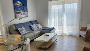 A modern living room with a glass coffee table, a grey sofa, wicker chairs, and a painting on the wall. - Detached Sea View Villa on Gated Development. (Antigua)