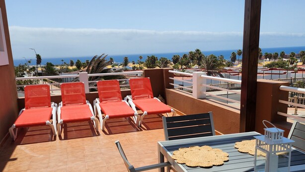 A terrace with red lounge chairs, a table with bread, and a view of the ocean. - Detached Sea View Villa on Gated Development. (Antigua)