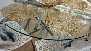 A round glass table with intricate woven placemats and white chairs with a lattice design. - Detached Sea View Villa on Gated Development. (Antigua)