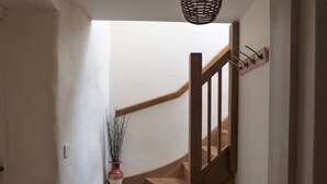 Una escala de fusta amb barana, una planta en test i una làmpada.