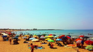 A crowded beach with numerous colorful umbrellas and people enjoying the water.