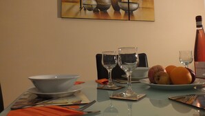 A dining table with a bowl, wine glasses, a bottle, and a plate of fruit.