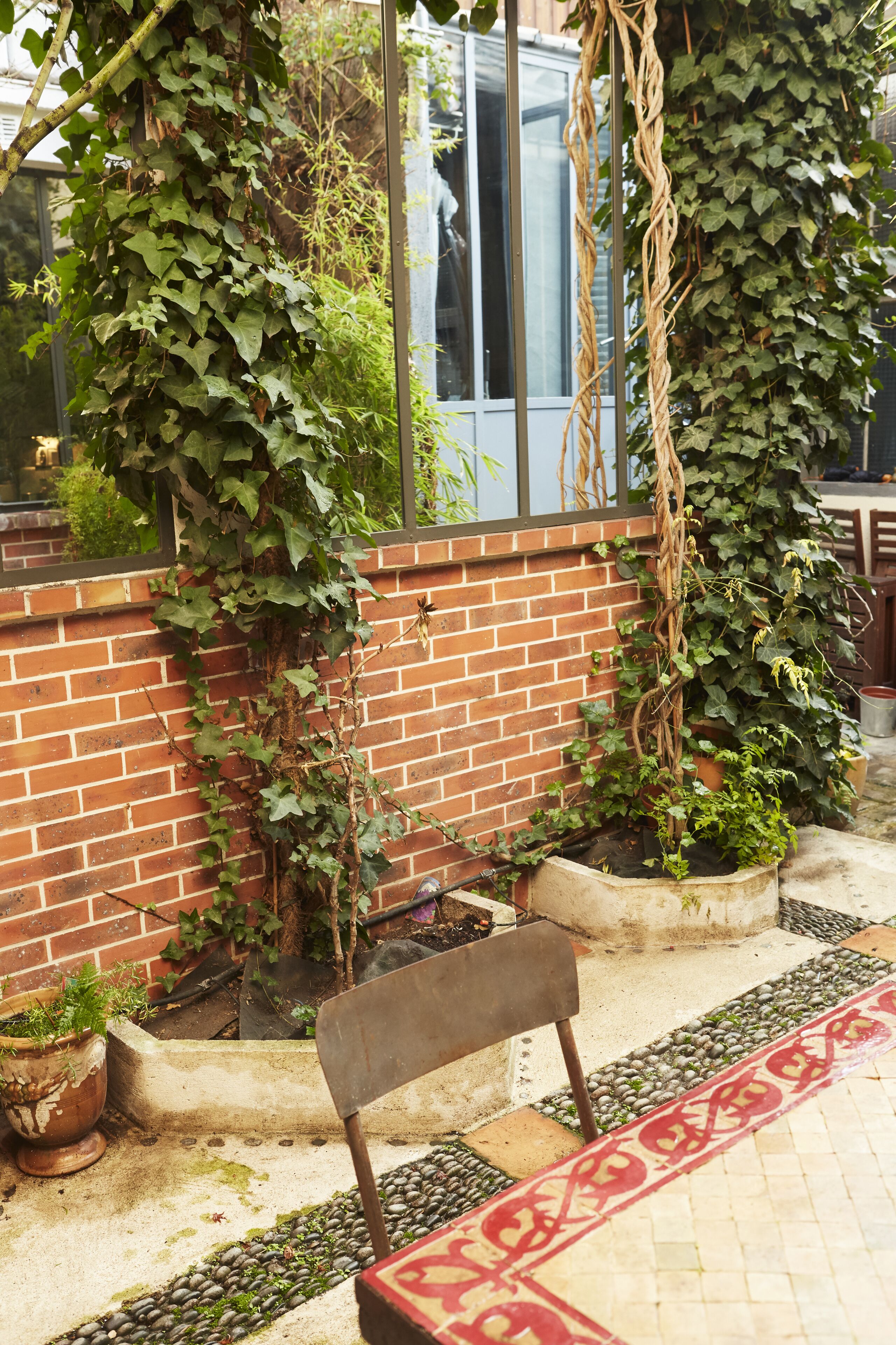 Un muro de ladrillo con un banco y plantas en macetas.