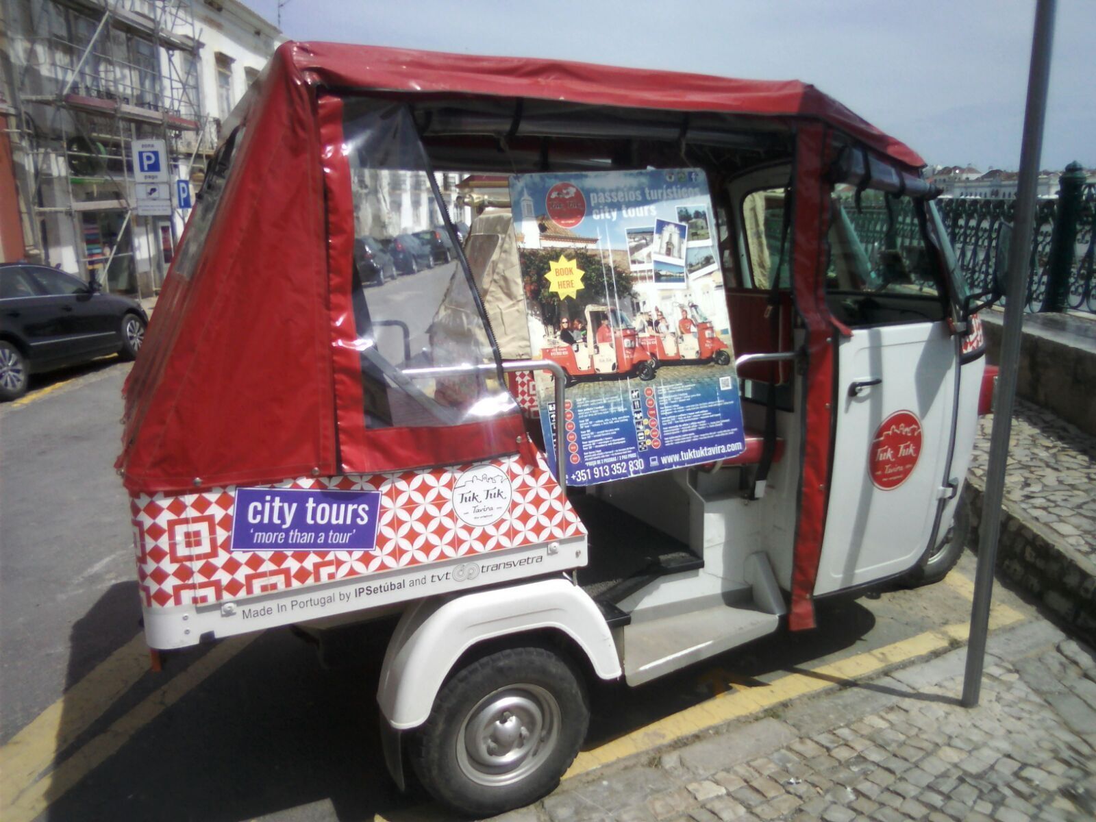 Un tuk-tuk con publicidad de tours por la ciudad, un número de contacto y una dirección web.