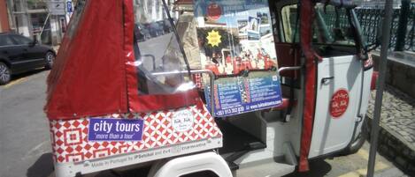 Un tuk-tuk con publicidad de tours por la ciudad, un número de contacto y una dirección web.