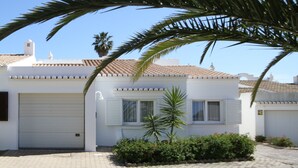 A two-story house with a white exterior, a tiled roof, and a small garden with plants and flowers. - Villa Meia-Praia, with Terrace, Pool and Garden (Lagos)