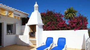 A rooftop terrace with two blue lounge chairs, a white chimney, and pink bougainvillea flowers. - Villa Meia-Praia, with Terrace, Pool and Garden (Lagos)