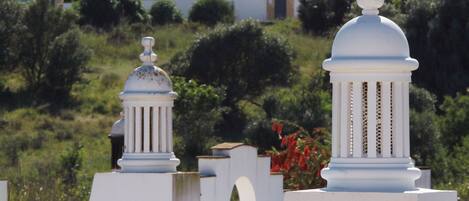 A white building with a dome and columns, surrounded by greenery and a residential area.