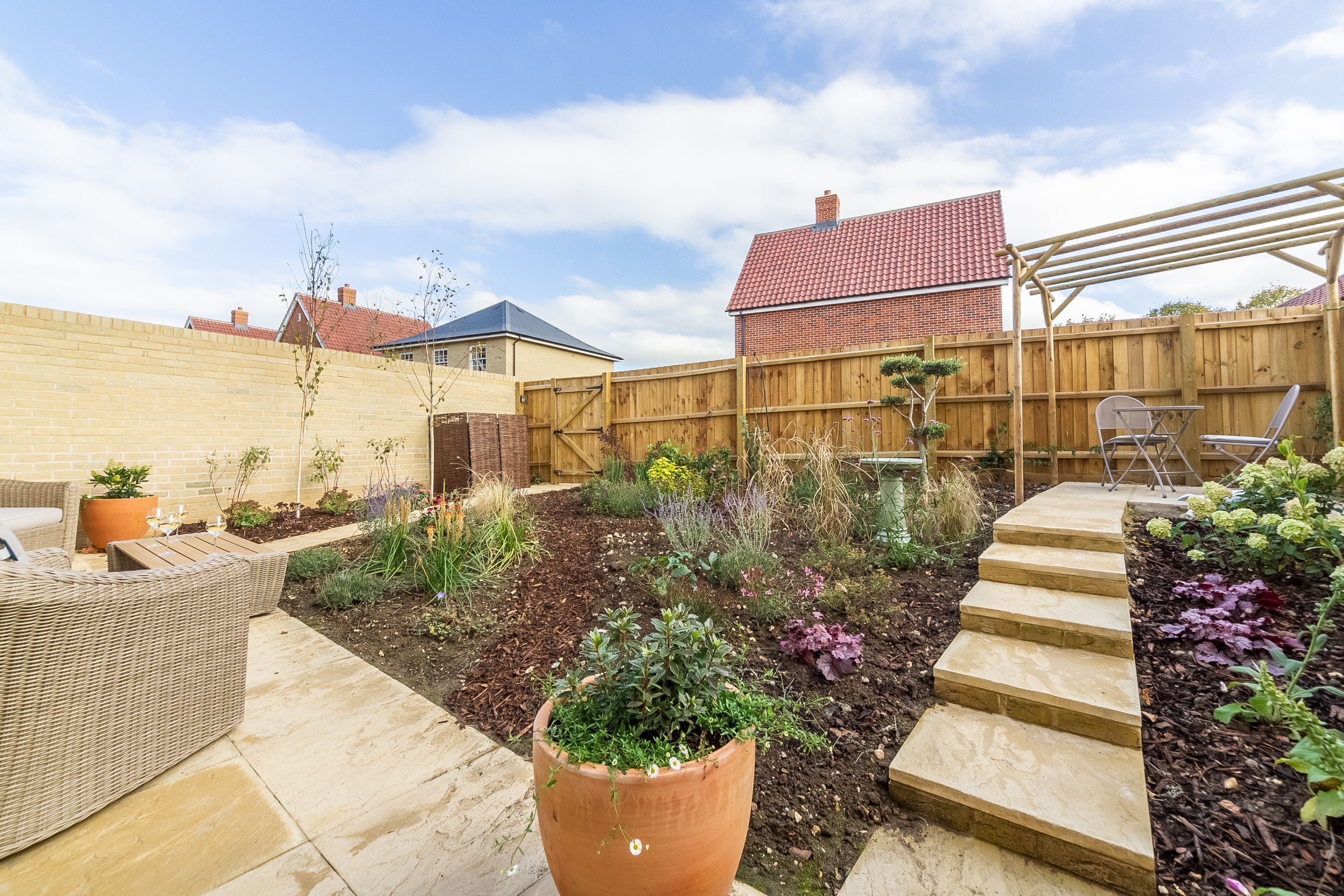 Un jardin avec un espace patio, une clôture en bois et une pergola.