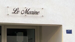 A building entrance with a sign reading "Le Marine" and a blue number plate indicating the address.