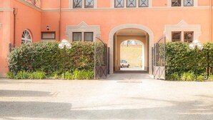 En stor, ferskenfarvet bygning med en symmetrisk facade, mange vinduer med dekorative rammer og en central, buet indgang.