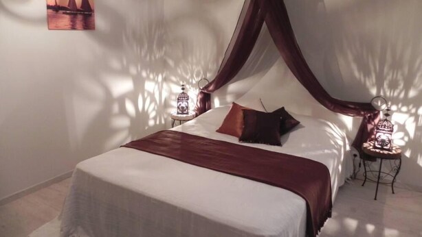 Ein Schlafzimmer mit einem Bett, einem Baldachin, zwei Nachttischen und einer Wandlampe.