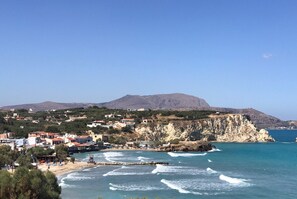 Une ville côtière dotée d’une plage, de falaises rocheuses et d’une montagne en arrière-plan.