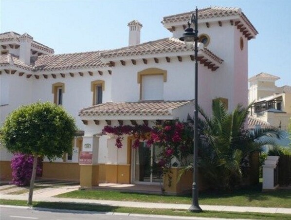 A two-story building with a tiled roof and a balcony.
