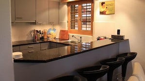 Una cucina moderna con un piano di lavoro nero, una finestra con persiane e un cartello appeso al muro.