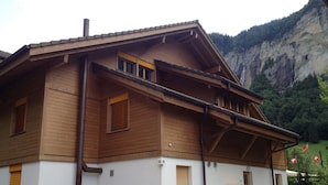 Un edificio in legno a due piani con tetto spiovente, un piccolo balcone e una porta con una cassetta postale.