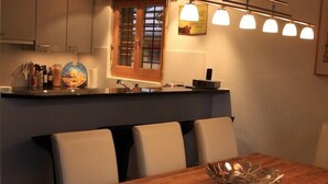 Una cucina moderna con tavolo e sedie in legno, illuminazione a soffitto e una finestra con persiane.