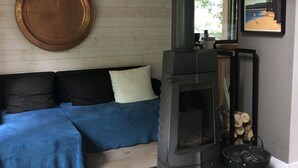 Ein gemütliches Wohnzimmer mit einer Couch, einem großen runden Spiegel, einem Kamin und einem Bild an der Wand.