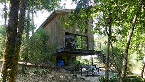 Eine moderne Holz-Blockhütte mit Balkon, umgeben von Bäumen.