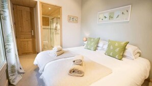 A bedroom with a large bed, a wooden door, and a shower area. - Apartment la Ranche, Montriond (Montriond)