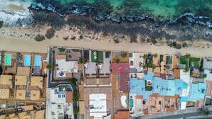 An aerial view of a coastal hotel with multiple buildings, a beach, and a road with cars. - Private, independent villa on the first line, terrace and tranquility
 (La oliva)