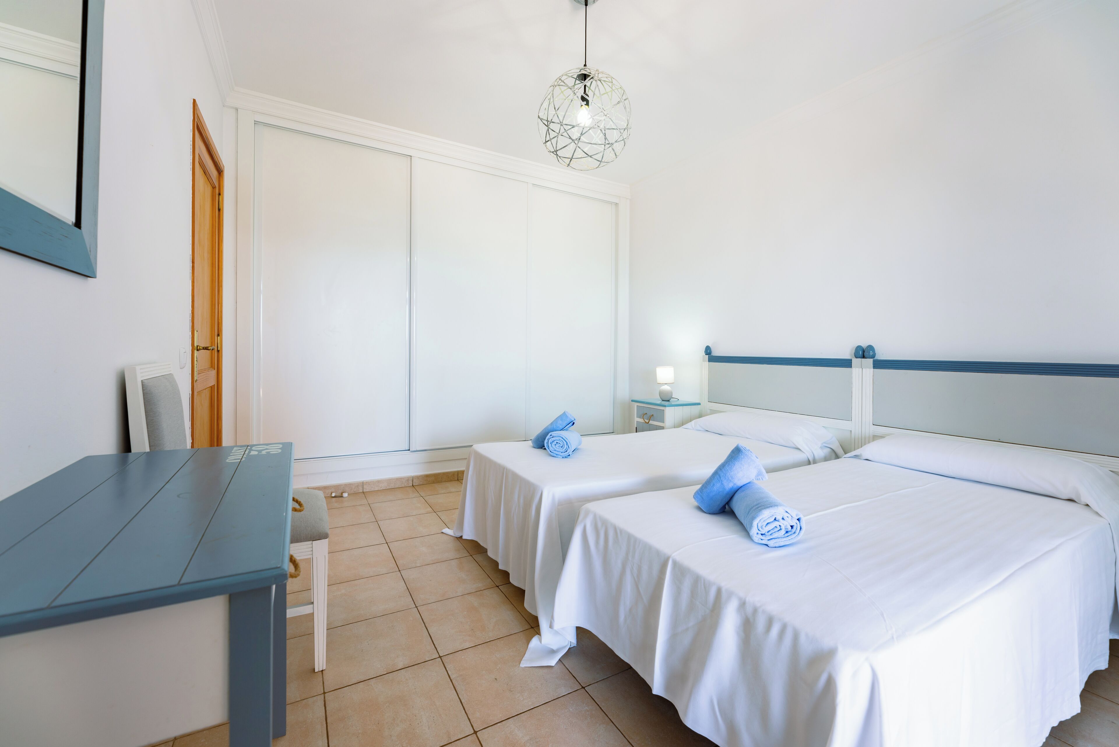 Una camera d'albergo con due letti, un tavolino e una sedia.