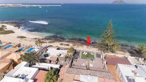 A coastal hotel with multiple swimming pools, a beach, and a view of the sea.