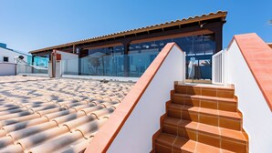 A modern building with a tiled roof and a glass facade. - Private, independent villa on the first line, terrace and tranquility
 (La oliva)