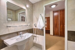 A bathroom with a sink, mirror, towel rack, and a shower area.