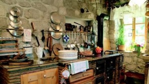 Une cuisine rustique avec des murs en pierre, des armoires en bois et divers ustensiles et ustensiles de cuisine.
