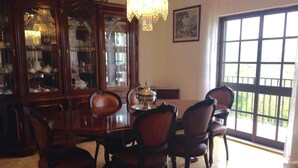 A dining room with a large wooden table, six chairs, a chandelier, and a large window with a view. - Spacious Contemporay apartment in an independent villa (Porches)
