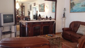 A living room with a brown leather sofa, a television, and a wooden cabinet with decorative items. - Spacious Contemporay apartment in an independent villa (Porches)