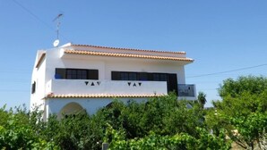 A two-story building with a white facade, a tiled roof, and a satellite dish. - Spacious Contemporay apartment in an independent villa (Porches)
