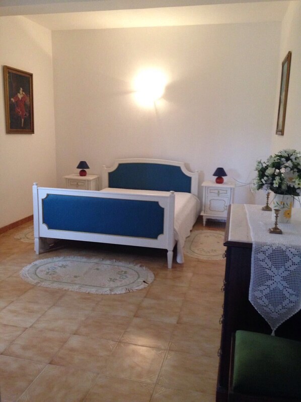 A bedroom with a bed, bedside tables, a nightstand, a lamp, a vase with flowers, and a framed picture on the wall. - Spacious Contemporay apartment in an independent villa (Porches)