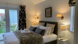 A bedroom with a bed, two bedside lamps, a framed quote on the wall, and a window with curtains.