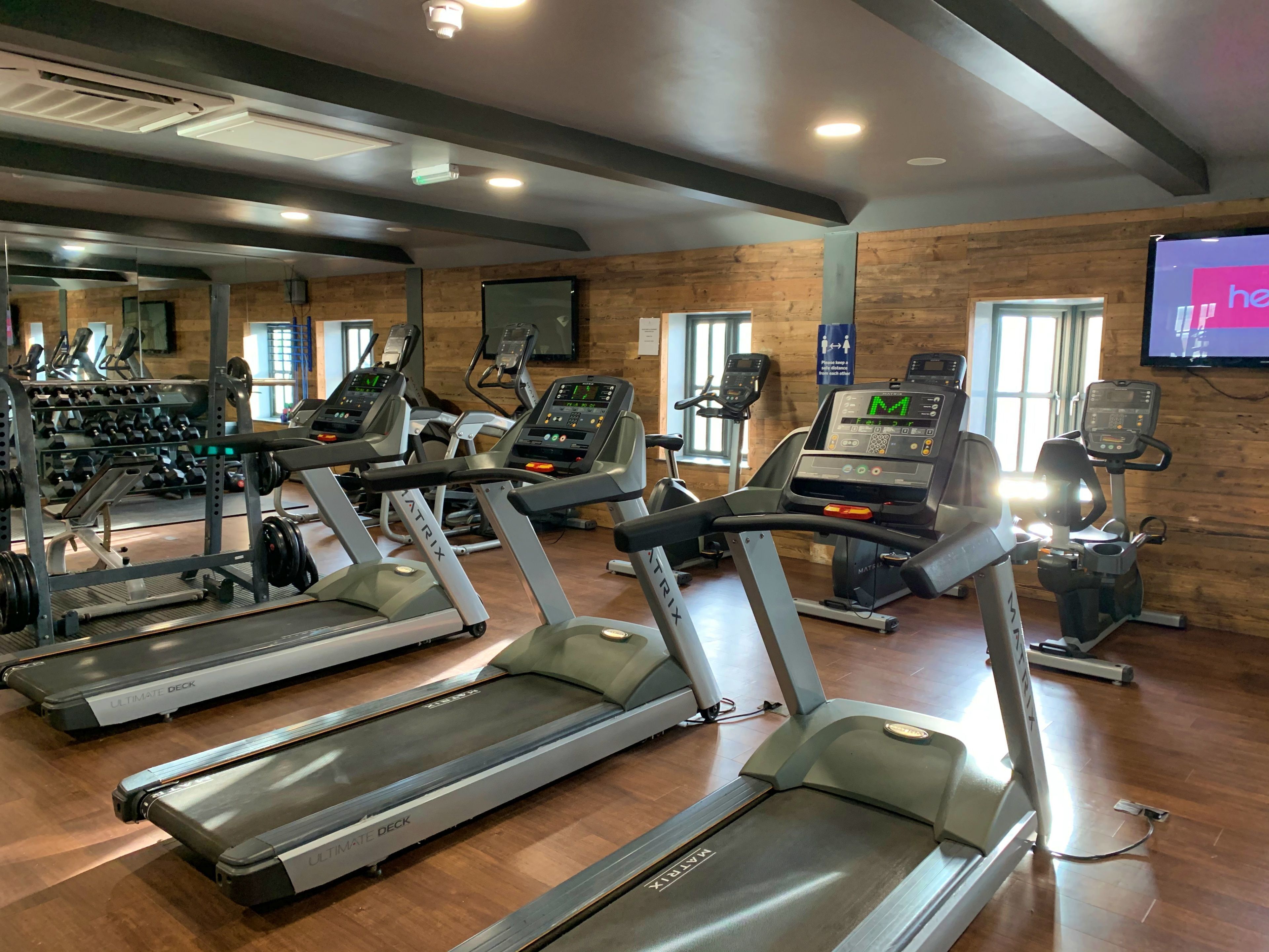 A gym with treadmills, weight machines, and a mirrored wall.