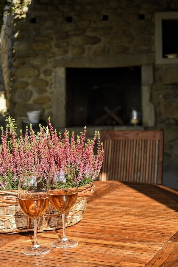 Une table en bois, avec deux verres à vin et un panier rempli de fleurs de bruyère.