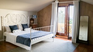 Un dormitorio con cama, mesita de noche, cómoda y balcón con vistas.